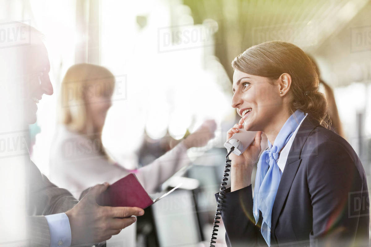 Customer service representative talking on telephone helping businessman at airport check-in counter Royalty-free stock photo