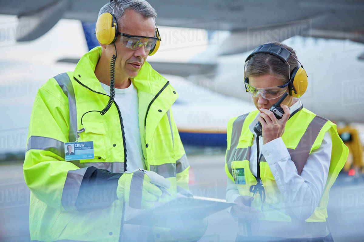 Air traffic control ground crew workers with clipboard talking on