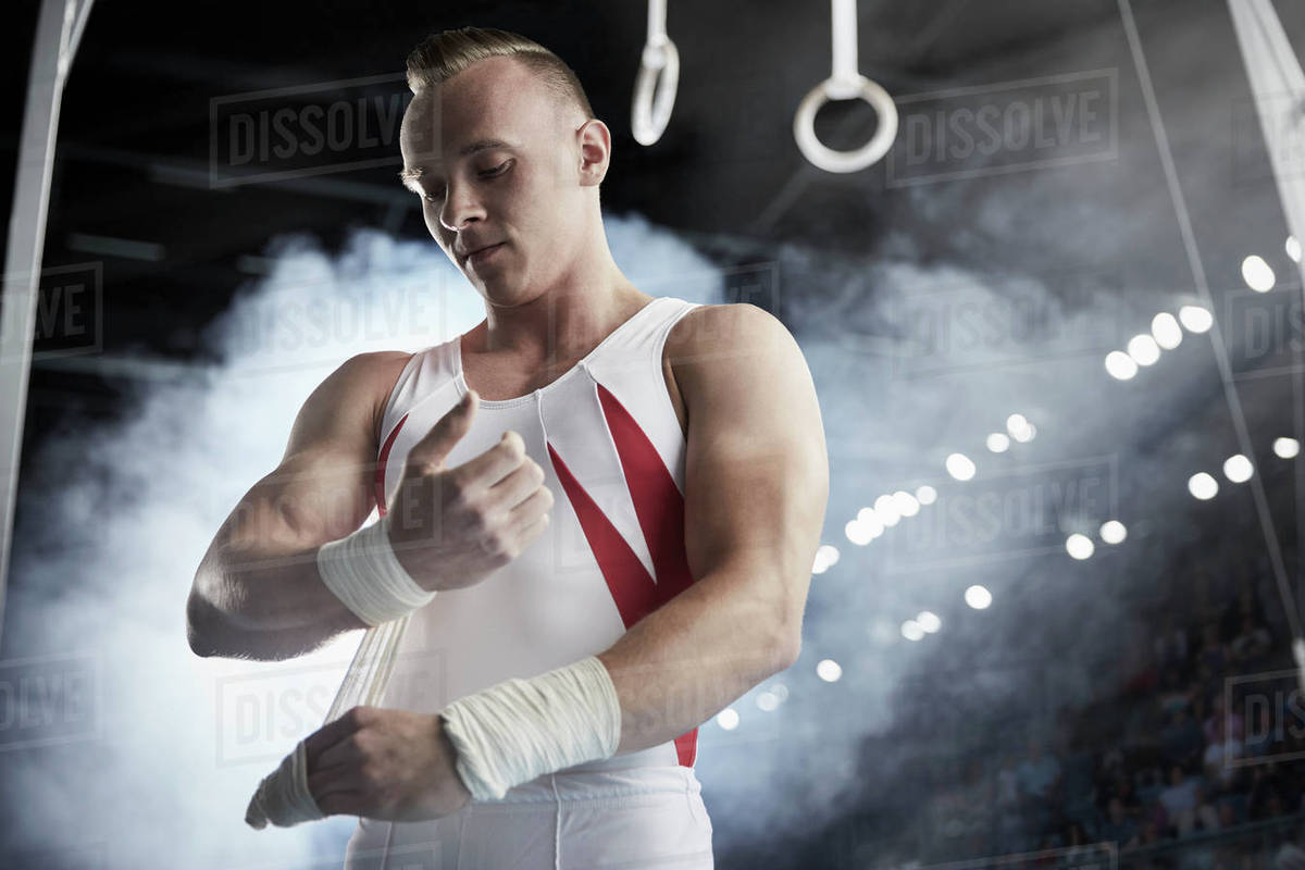Male gymnast wrapping wrists below gymnastics rings Stock Photo