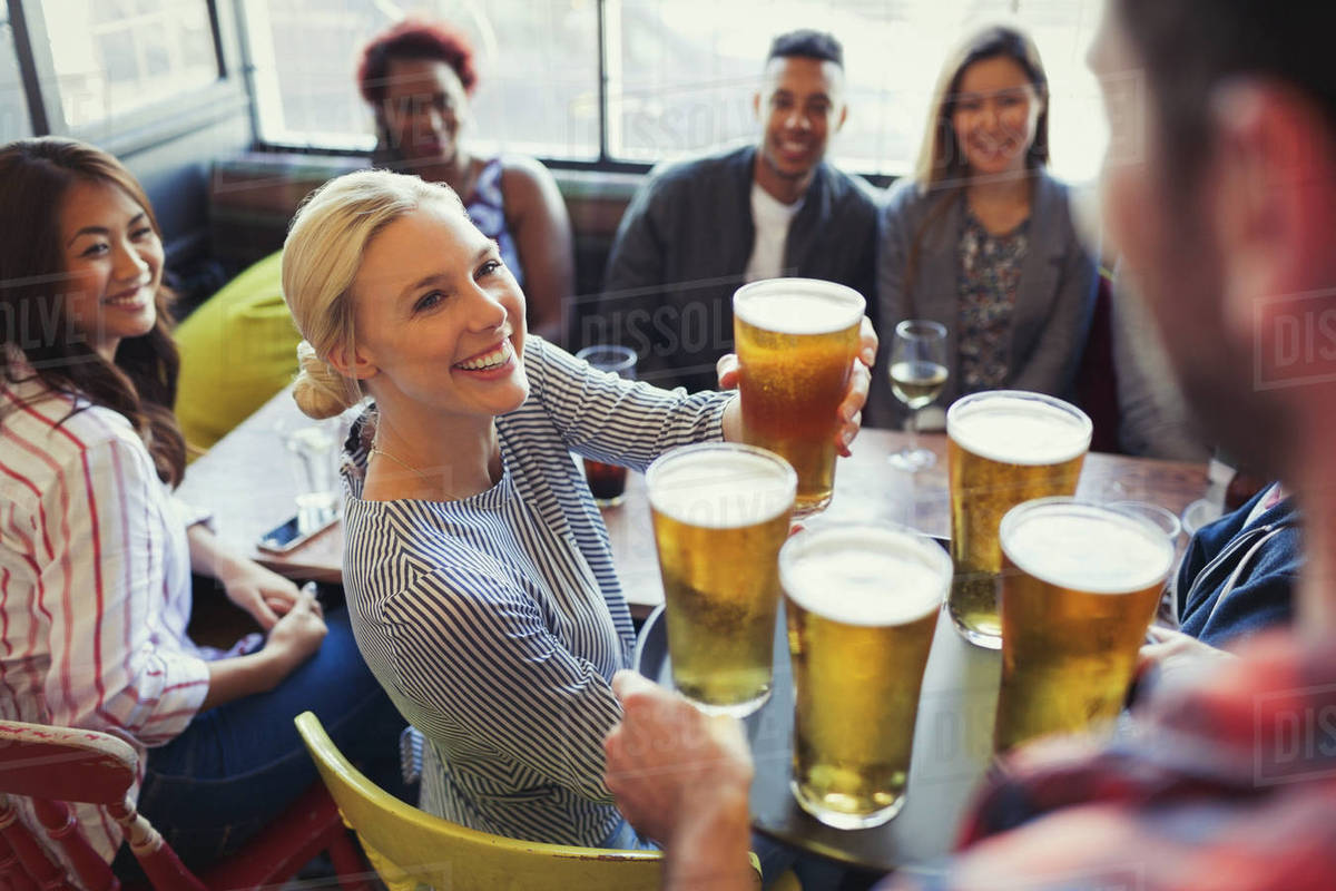 Bartender serving beers on tray to friends in bar Stock Photo Dissolve