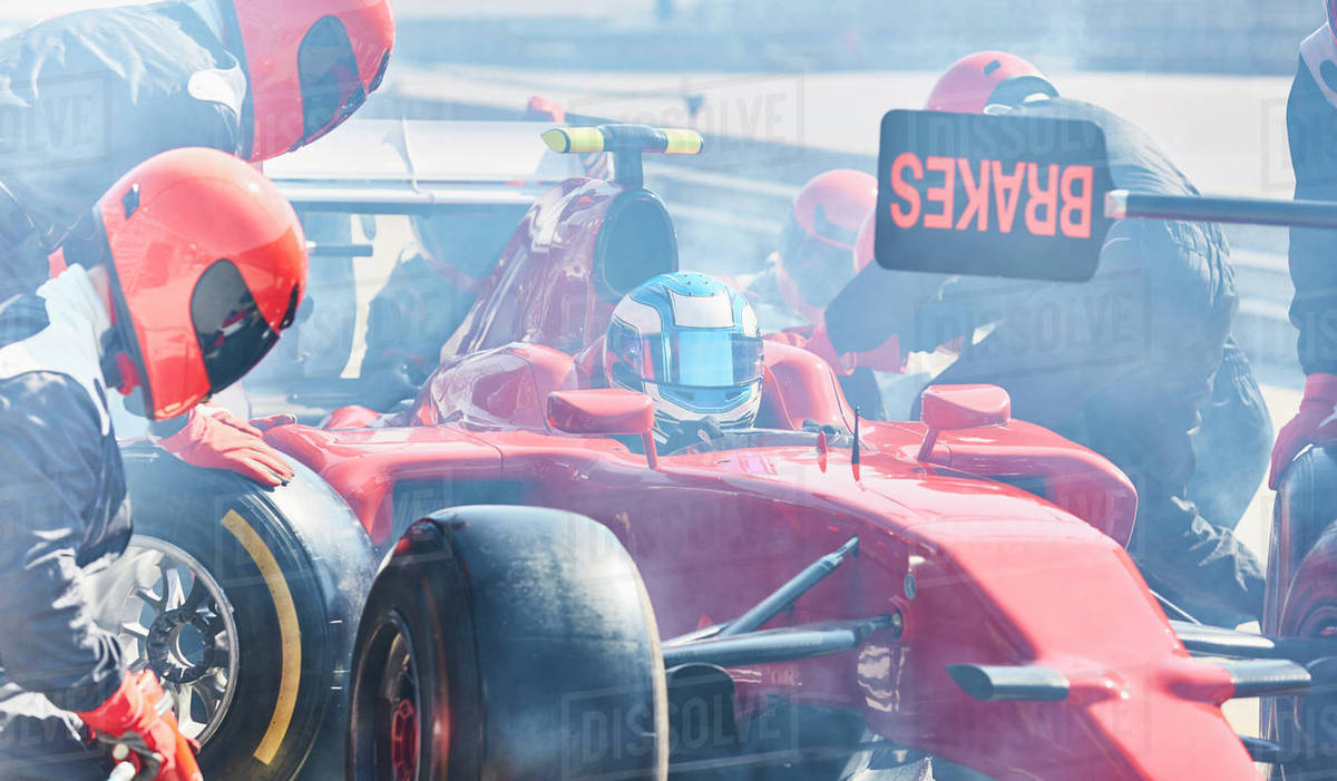 Pit crew replacing tires on formula one race car in pit lane Royalty-free stock photo