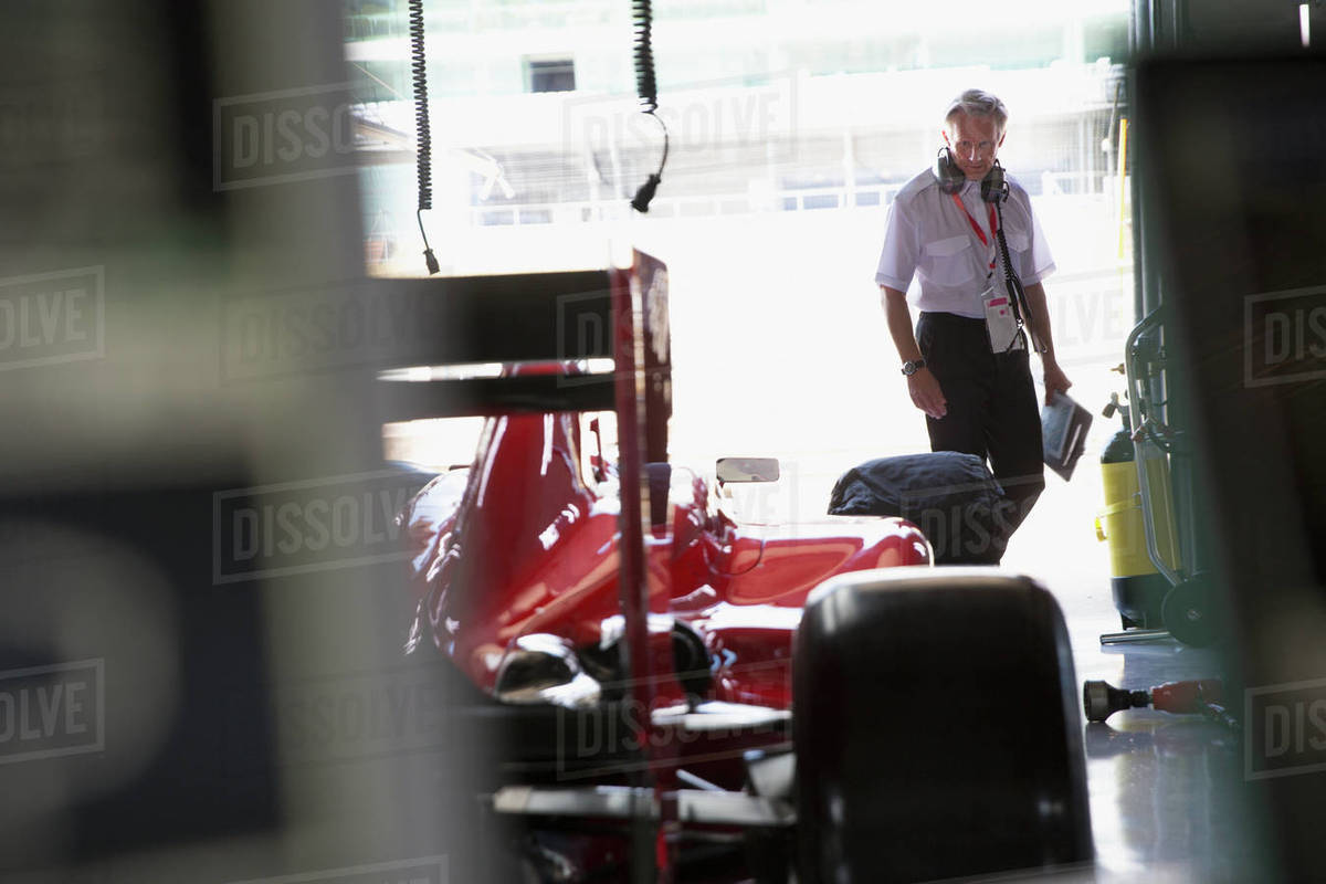 Manager examining formula one race car in repair garage Royalty-free stock photo