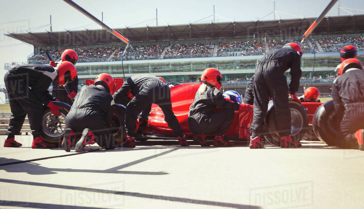 Pit crew replacing tires on formula one race car in pit lane Royalty-free stock photo