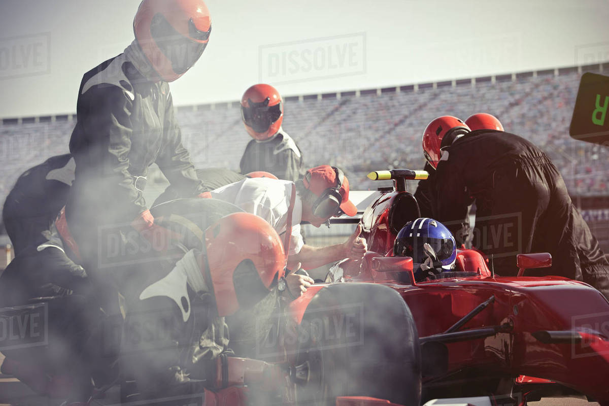 Pit crew replacing tires on formula one race car in pit lane Royalty-free stock photo