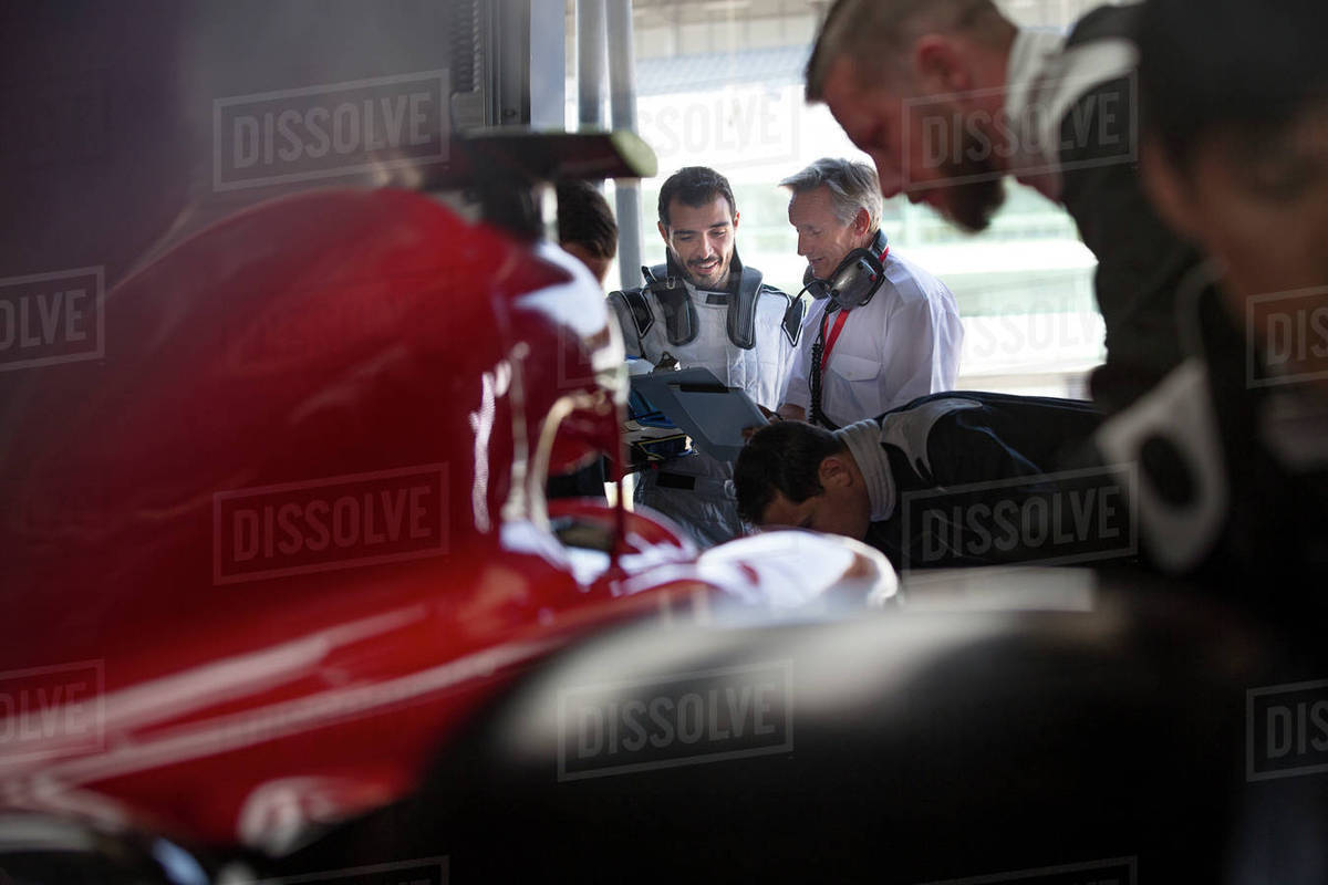 Manager and formula one race car driver talking in repair garage Royalty-free stock photo