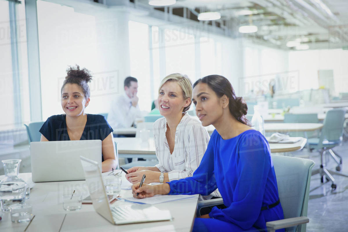 Businesswomen at laptops listening in office meeting Stock Photo