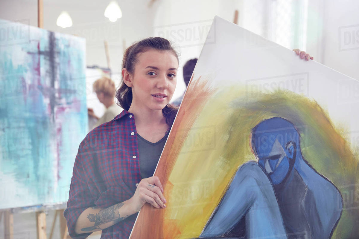 Portrait female artist holding, showing painting in art class studio