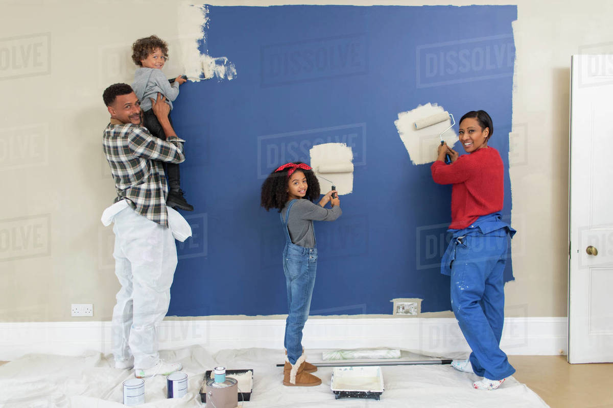 Portrait happy family painting wall - Stock Photo - Dissolve