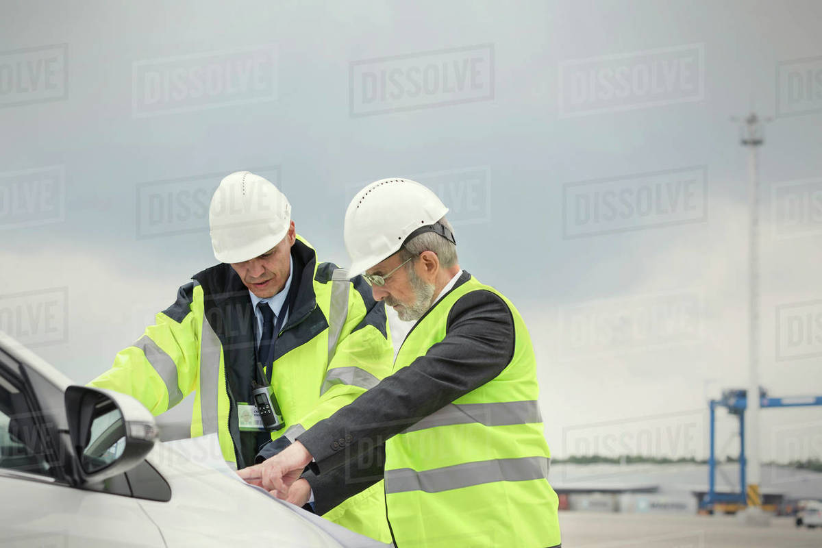 Dock worker and manager reviewing blueprint at shipyard Stock Photo