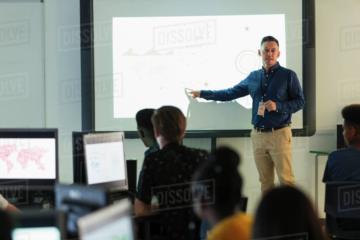 Male junior high teacher leading lesson at projection screen in classroom Stock Photo Dissolve