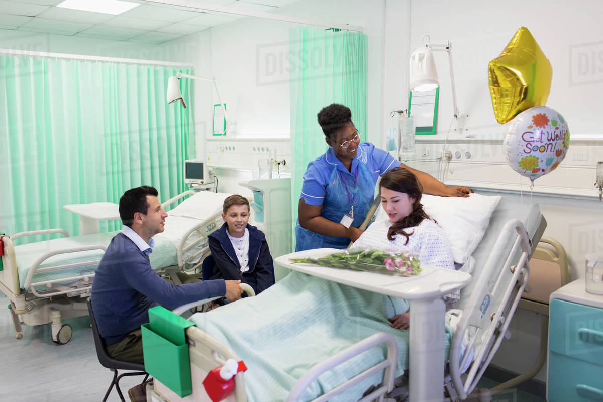 Nurse adjusting pillows for patient in hospital ward Stock Photo
