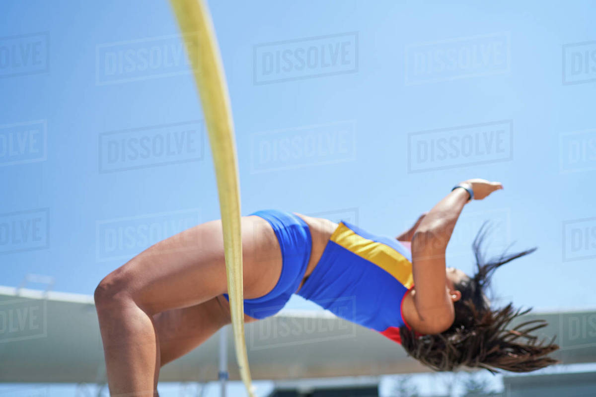 Female track and field athlete high jumping over pole Stock Photo