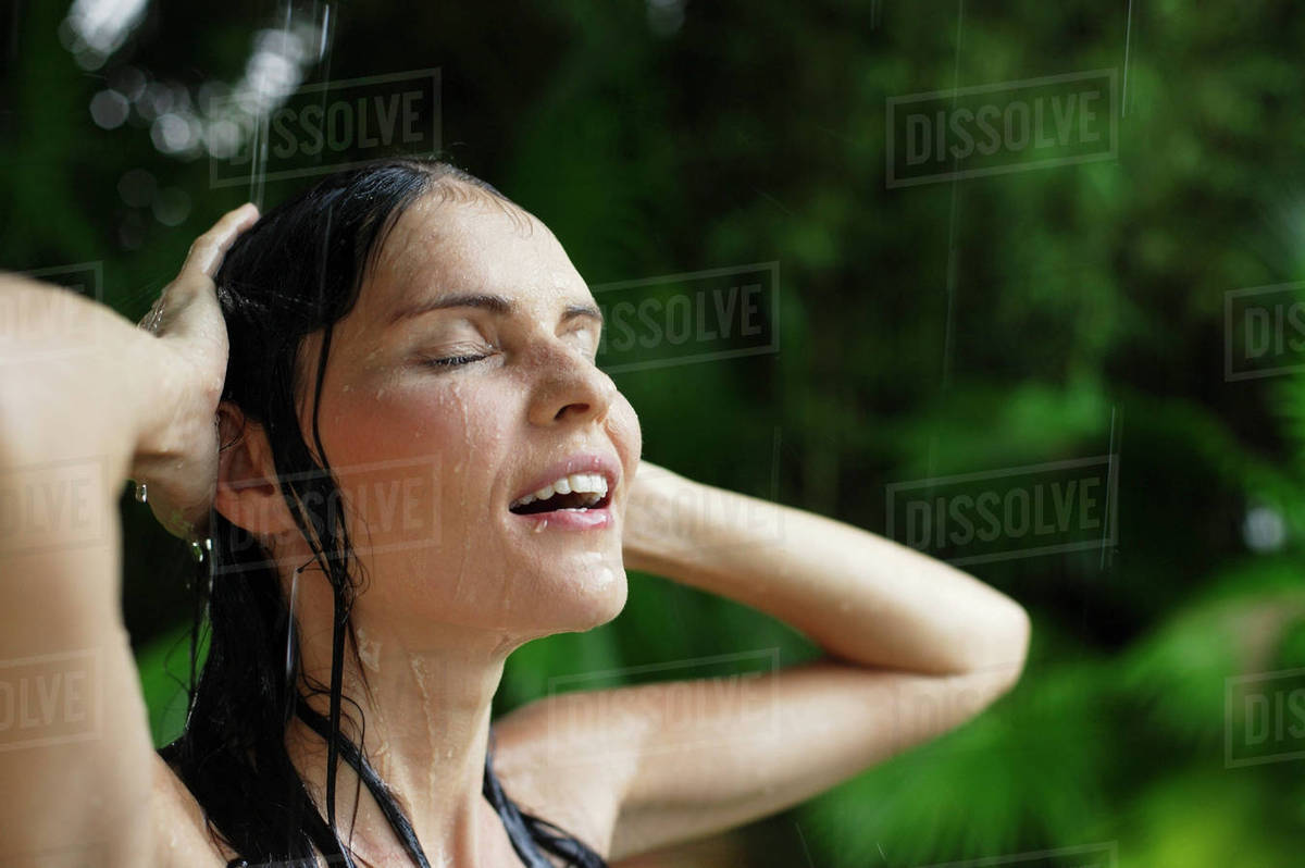 Woman in tropical rain shower, hands on head Stock Photo Dissolve