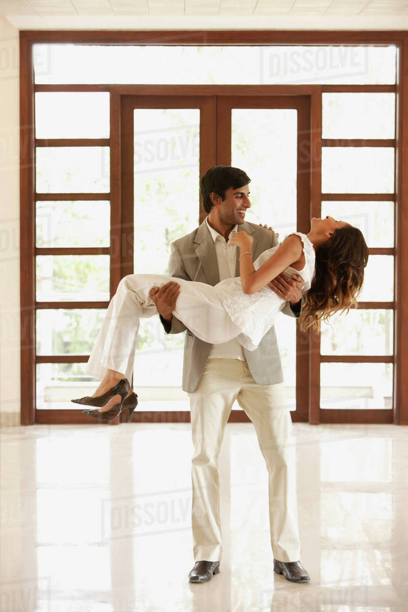 Man carrying woman over threshold into empty home Stock Photo Dissolve