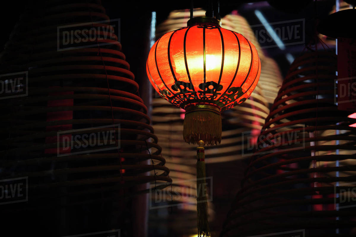 Red lantern with incense coils in foreground Stock Photo Dissolve