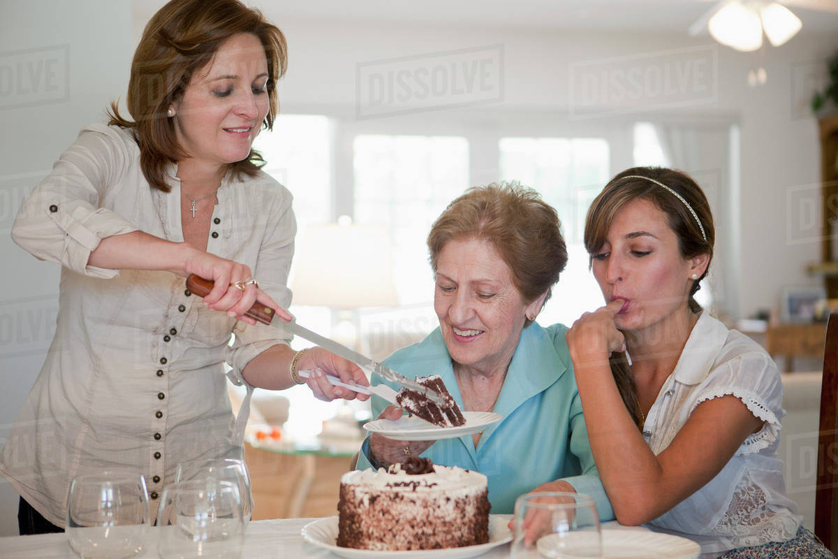 A woman serving cake for her mother and daughter Stock Photo Dissolve