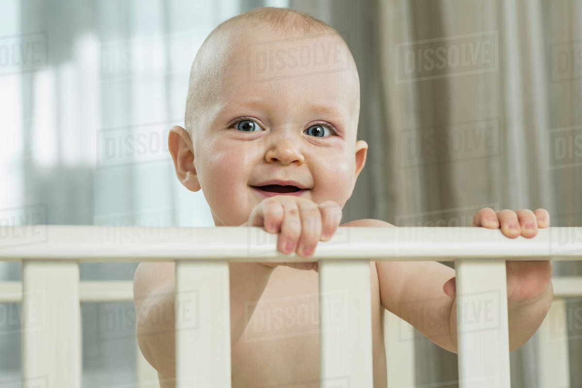 Baby standing in cot Stock Photo Dissolve