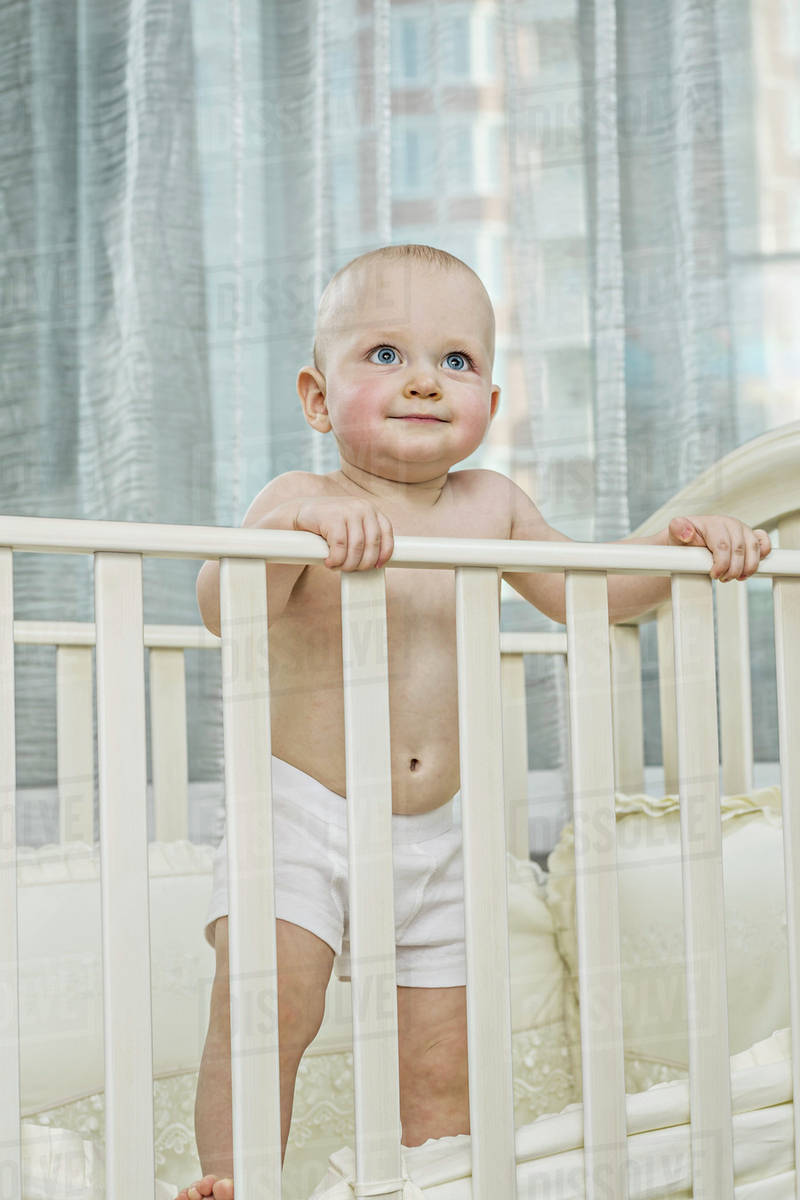 Baby standing up in cot Stock Photo Dissolve