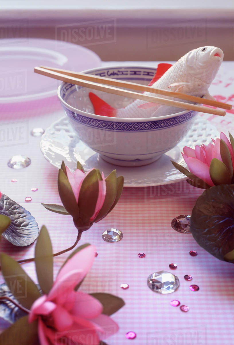 An artificial koi fish in a bowl set on a decorated table Stock Photo