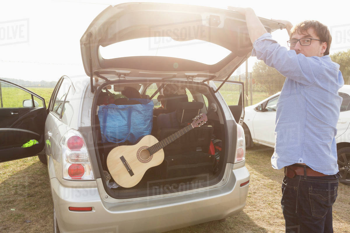 Side view of man closing car trunk Stock Photo Dissolve