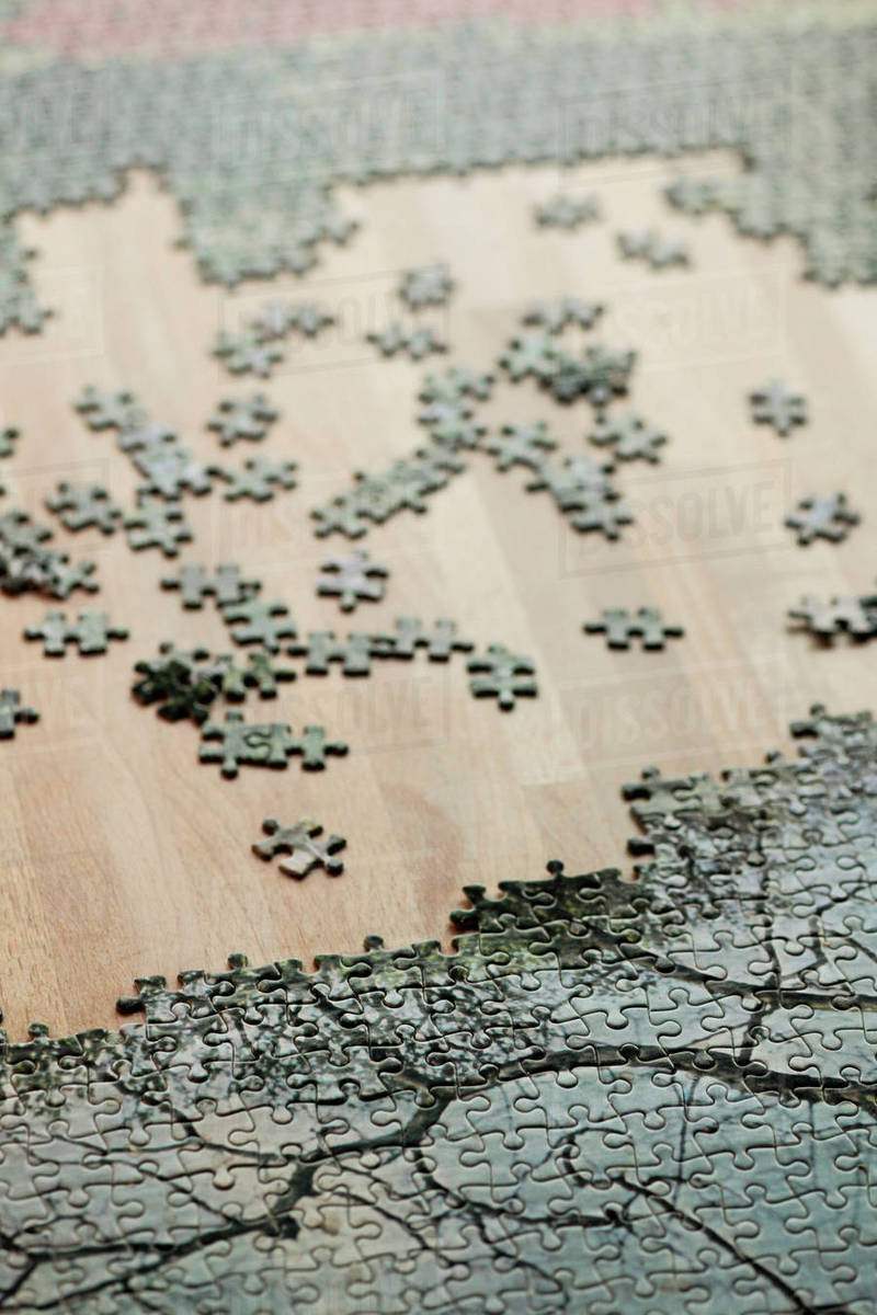 High Angle View Of Jigsaw Puzzle And Pieces On Wooden Table