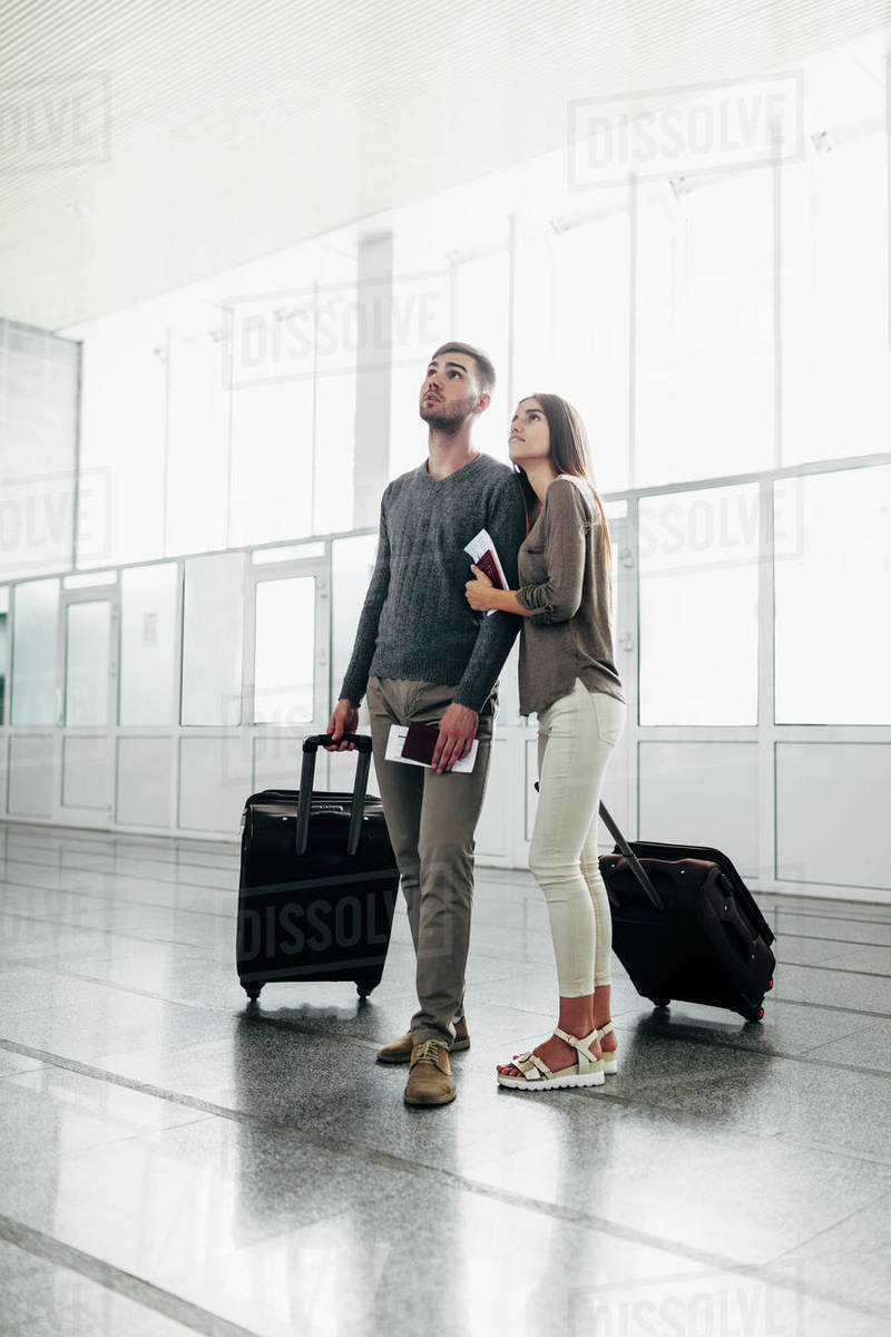 Full length of young couple with luggage and boarding passes at airport