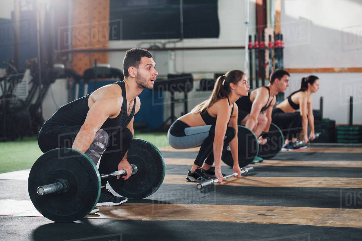Dedicated male and female athletes lifting barbells at gym Stock