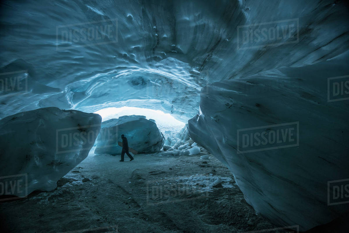 A man carrying snowboard while walking in ice cave, Whistler, British Columbia, Canada Royalty-free stock photo