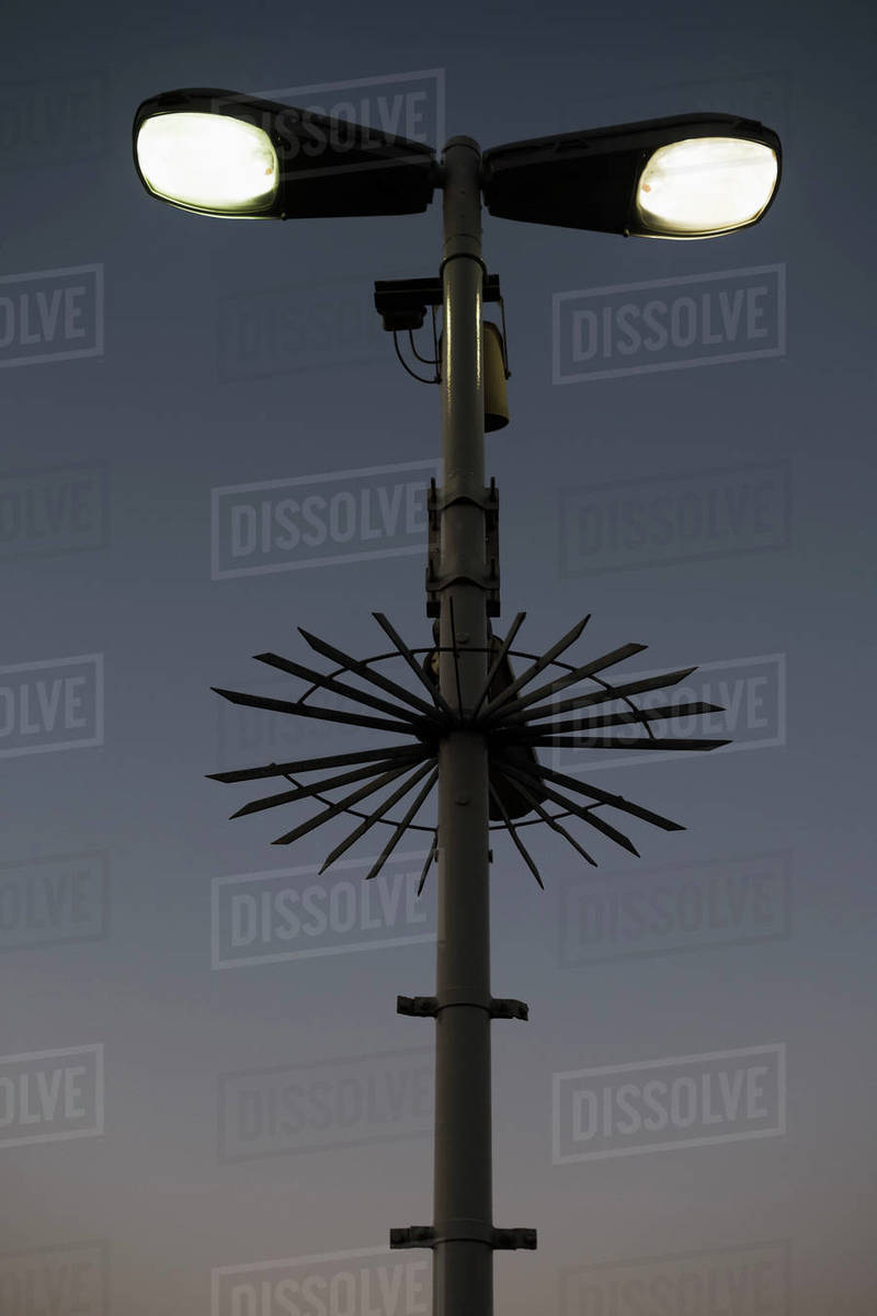 Low angle view of illuminated street light and surveillance cameras against sky Stock Photo