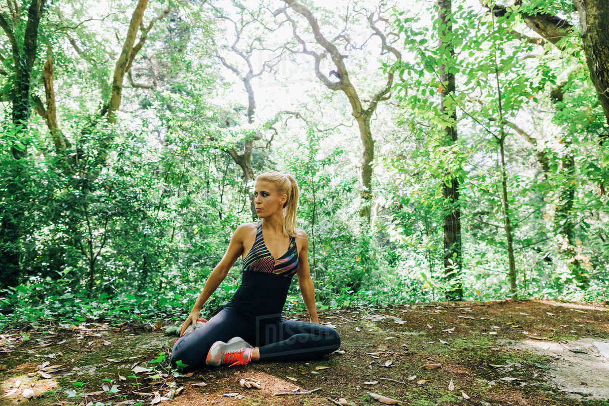 Fit female personal trainer exercising, stretching in forest Royalty-free stock photo