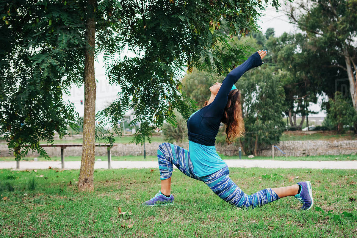 Fit female personal trainer exercising, stretching in park Royalty-free stock photo