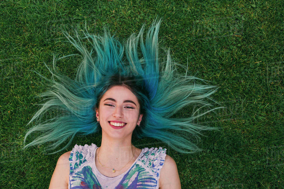 Overhead portrait carefree young woman with blue hair laying in grass Royalty-free stock photo