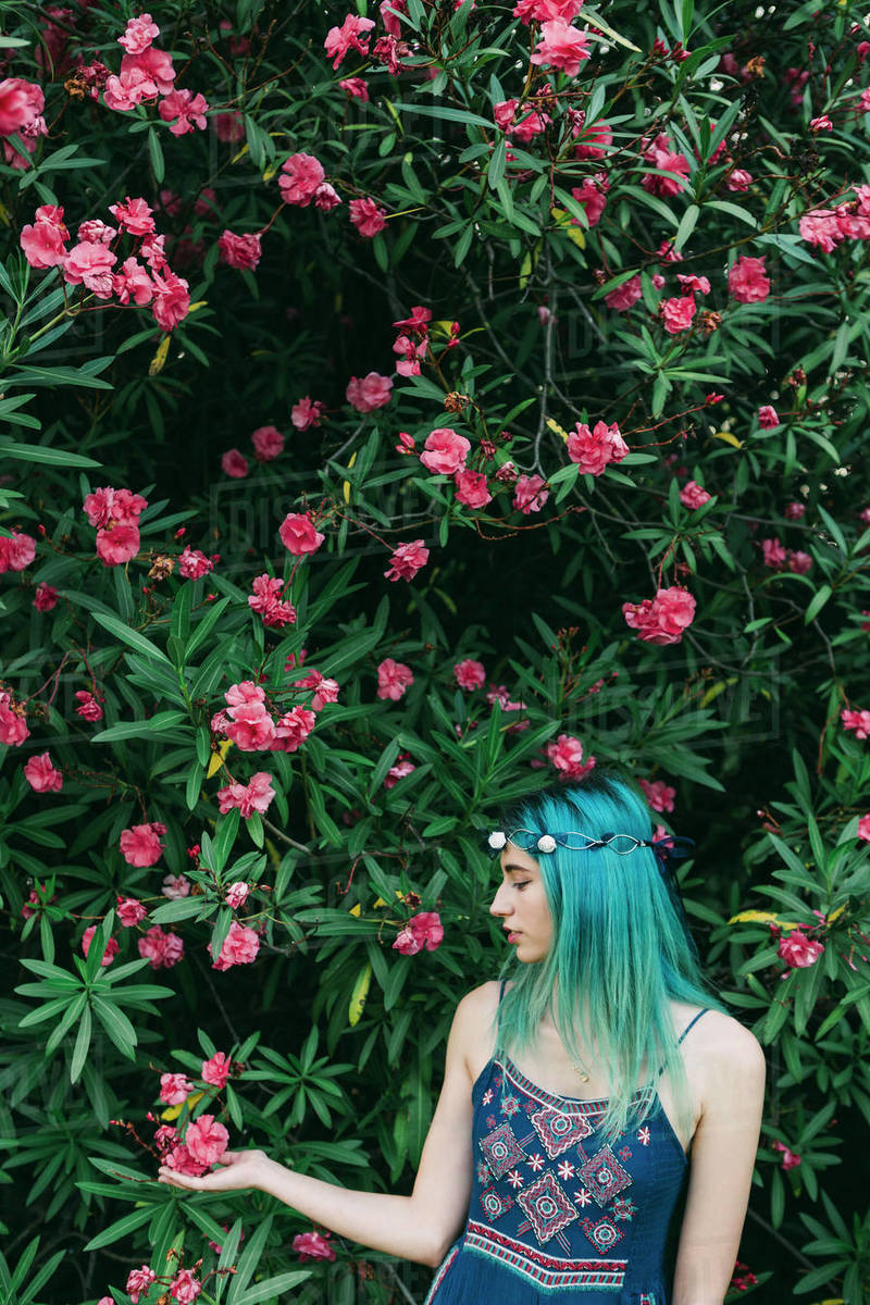 Serene young woman with blue hair standing below flowering tree Royalty-free stock photo