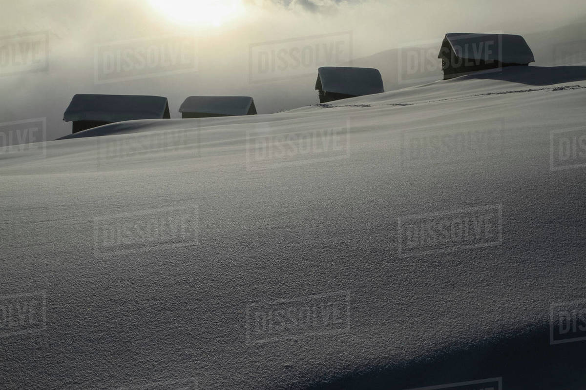 Snow covered cabins on sunny, tranquil mountain slope, Vella, Canton of Grisons, Switzerland Royalty-free stock photo