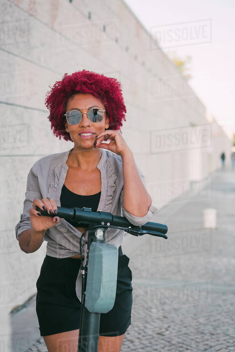 Portrait confident woman using shared public electric push scooter Royalty-free stock photo