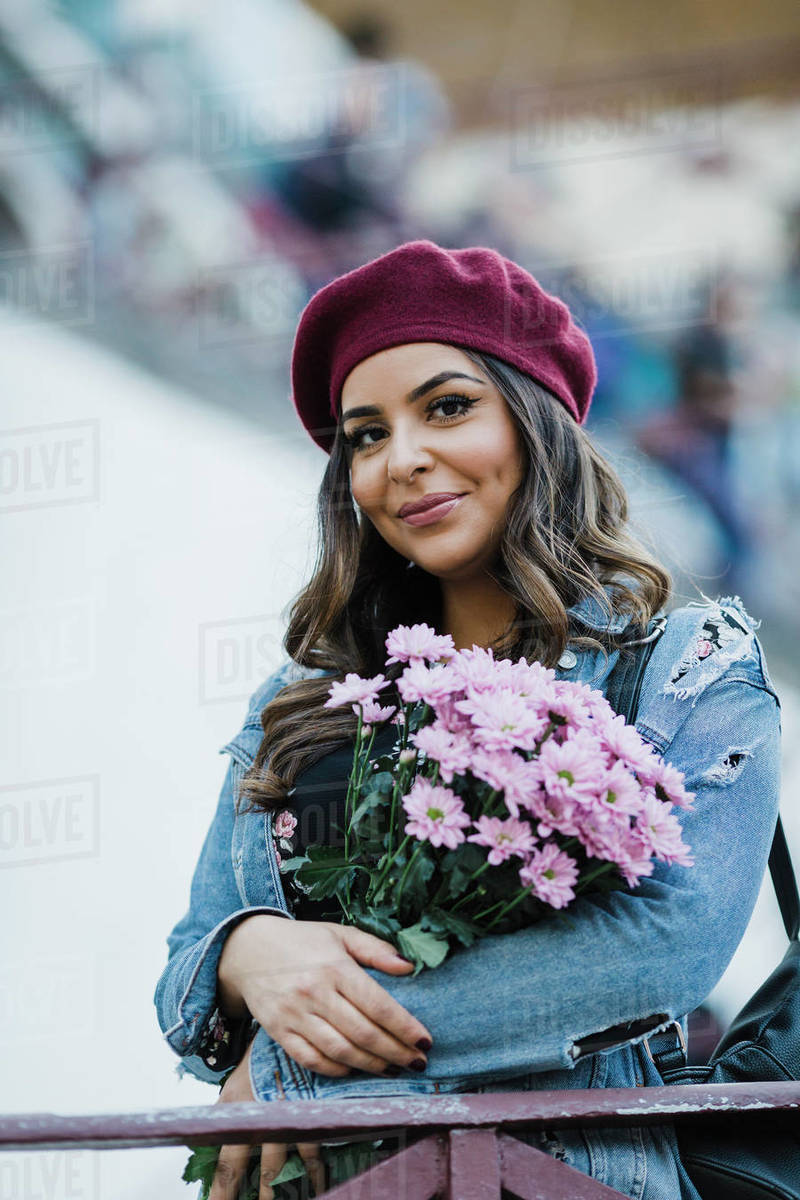 Portrait smiling young woman in beret holding flower bouquet Royalty-free stock photo