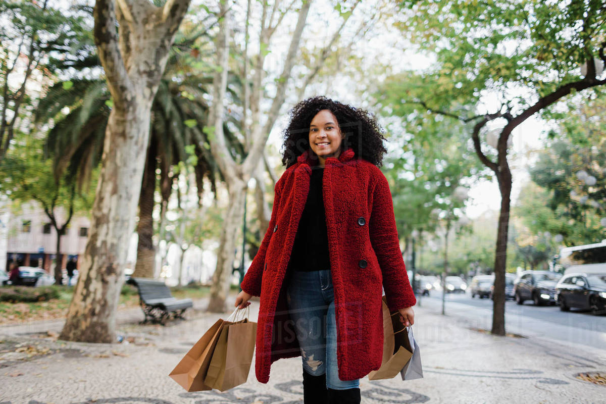 Portrait carefree young woman with shopping bags on urban sidewalk Royalty-free stock photo