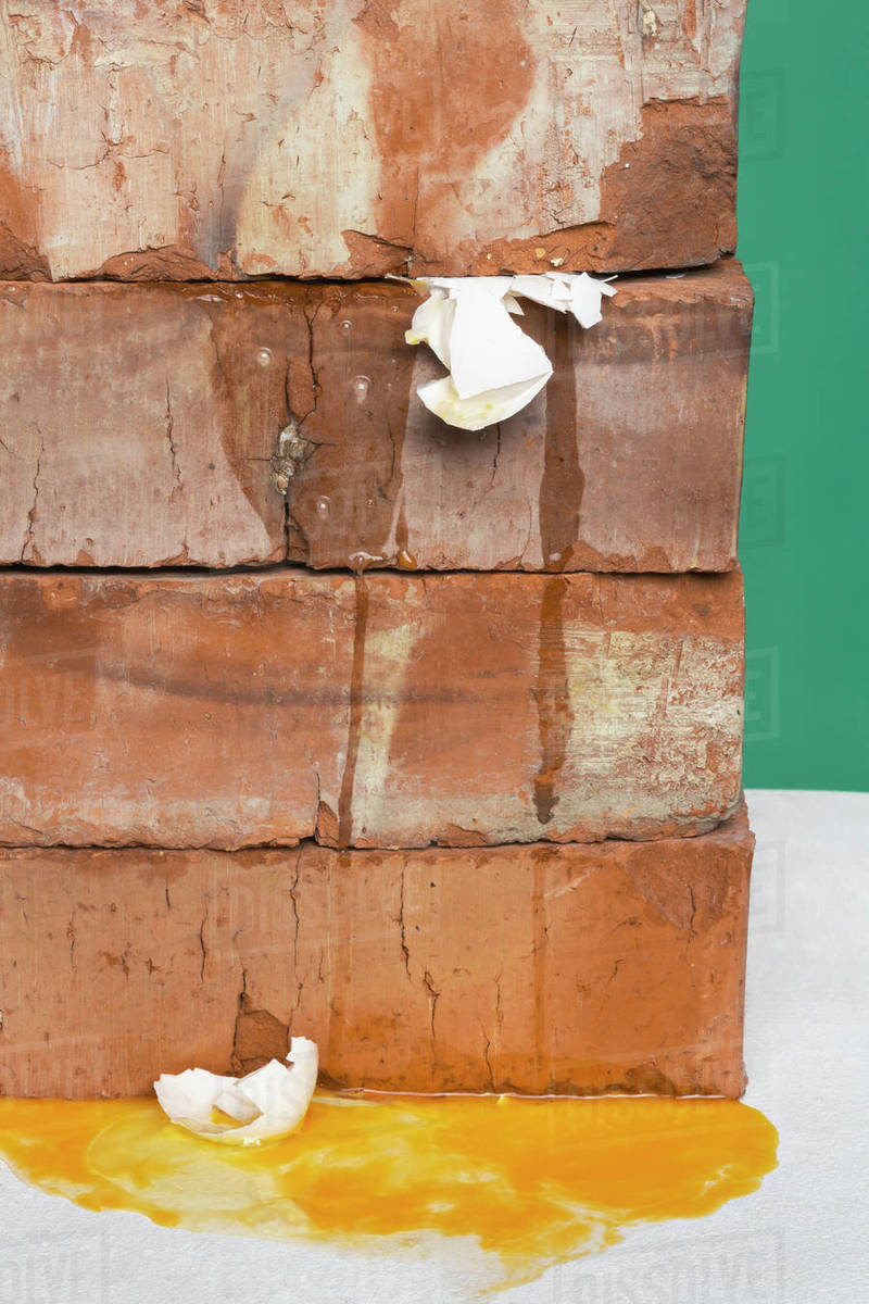 Bricks crushing eggs Stock Photo Dissolve