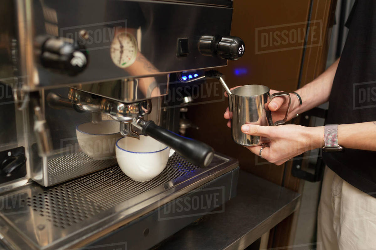 Barista steaming milk at espresso machine in cafe Stock Photo Dissolve