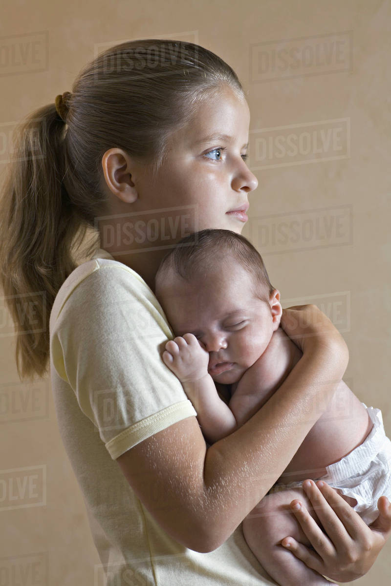 A young girl holding her baby sister closely Stock Photo Dissolve