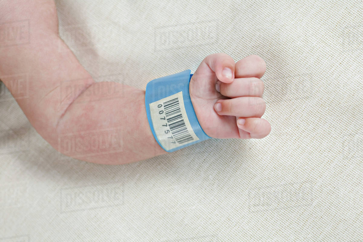 A hospital ID bracelet on a baby's wrist Stock Photo Dissolve